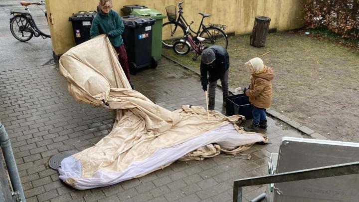 Tre spejdere der rengør et telt i regnvejr
