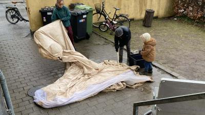 Tre spejdere der rengør et telt i regnvejr